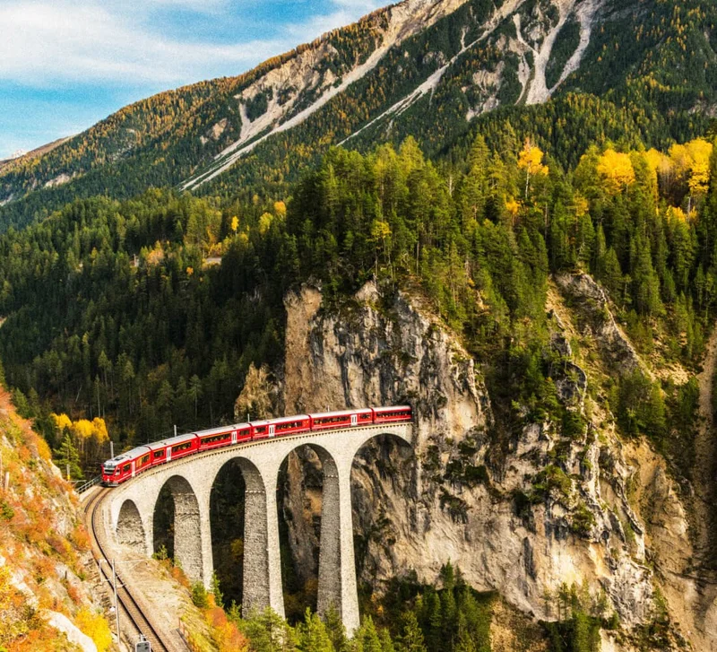 Image description: A red passenger train crossing a bridge