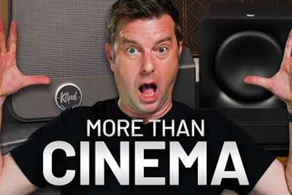 Man named Caleb, has his arms raised in surprise, with Klipsch Flexus products behind him. Claiming it’s more than cinema.