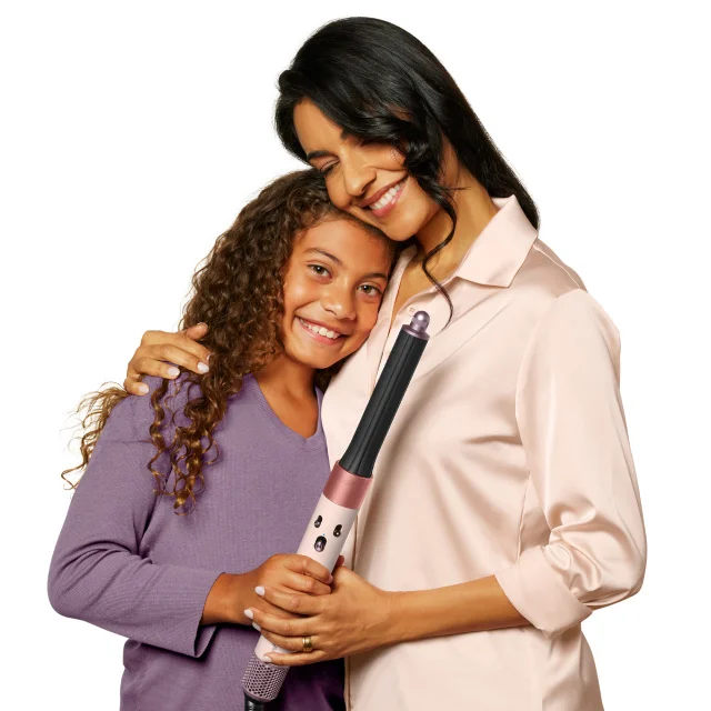 Mom and daughter hugging while holding a Dyson Airwrap multi-styler in Ceramic pink and rose gold