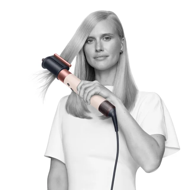 A model styling her hair with the Dyson Airwrap