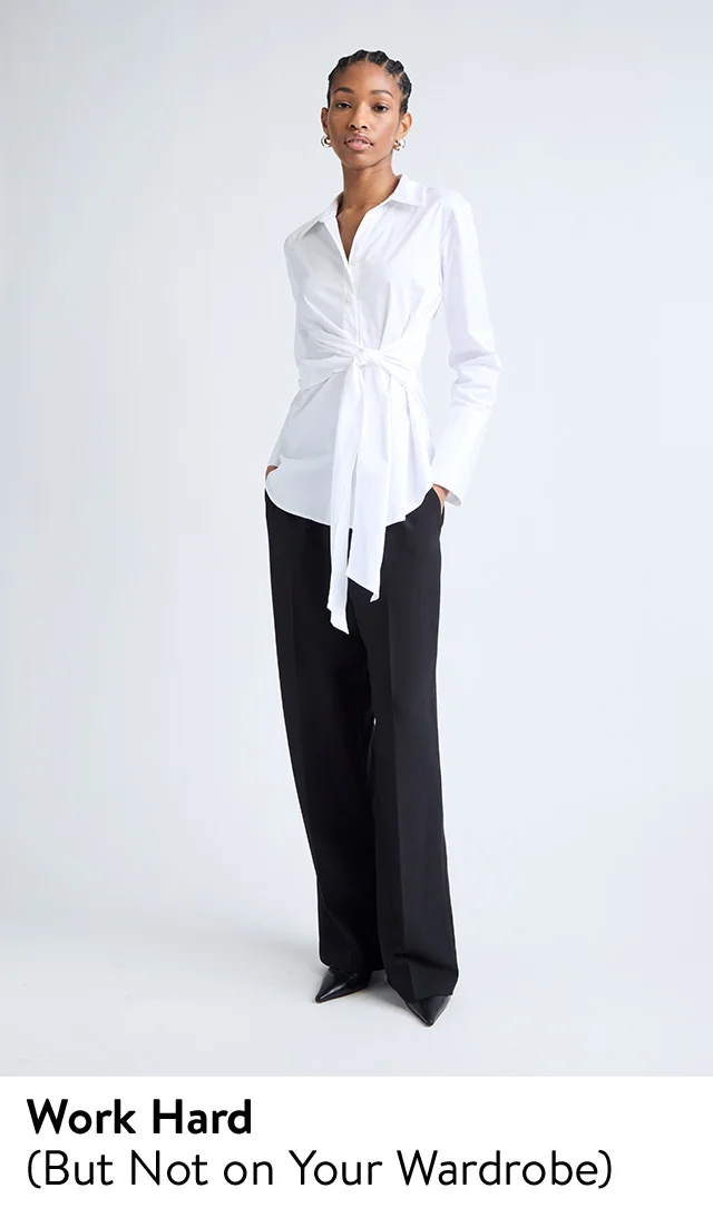 A woman wearing a wearing a button-up shirt with a tie detail, trousers & heels.