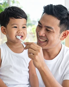 Father brushing toddler's teeth