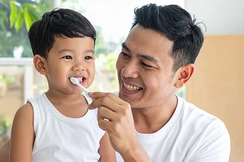 Father brushing toddler's teeth