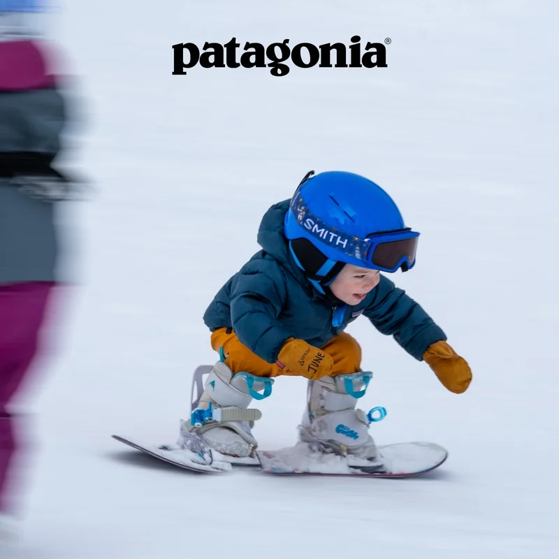 Patagonia. A young child squats low on their snowboard.