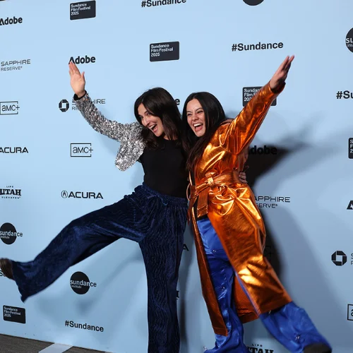 Two Festival attendees pose in front of a Step and Repeat.