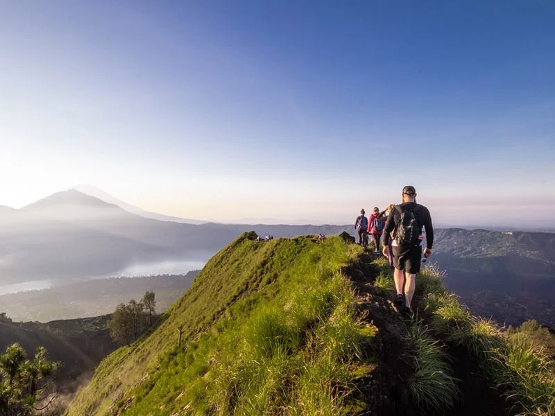 Hiking around the crater of Mount Batur with Mount Agung in the background.