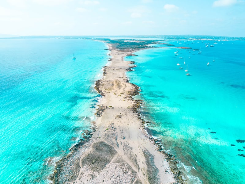 Aerial view above the paradise island of Formentera in Spain with narrow land and turquoise beach water.