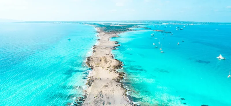 Aerial view above the paradise island of Formentera in Spain with narrow land and turquoise beach water.