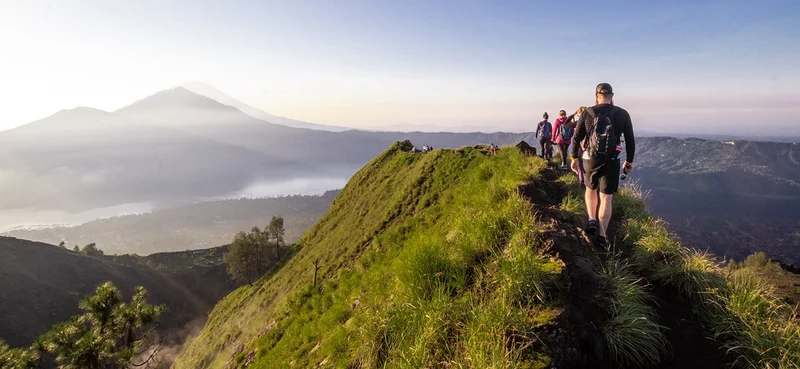 Hiking around the crater of Mount Batur with Mount Agung in the background.