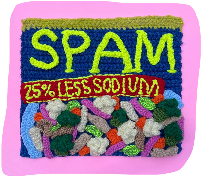 A square of croqueted yarn made to look like a box of Spam, overlaid on a pink background