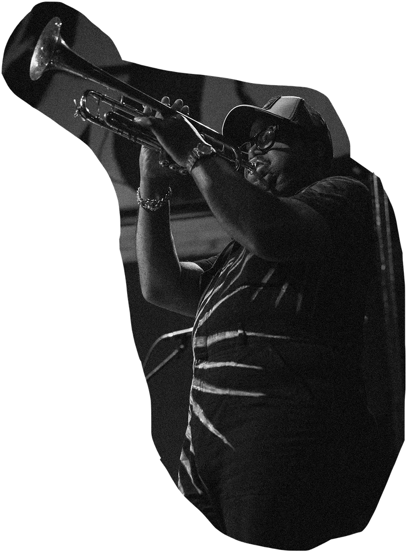 A man blows a trumpet while performing on a stage