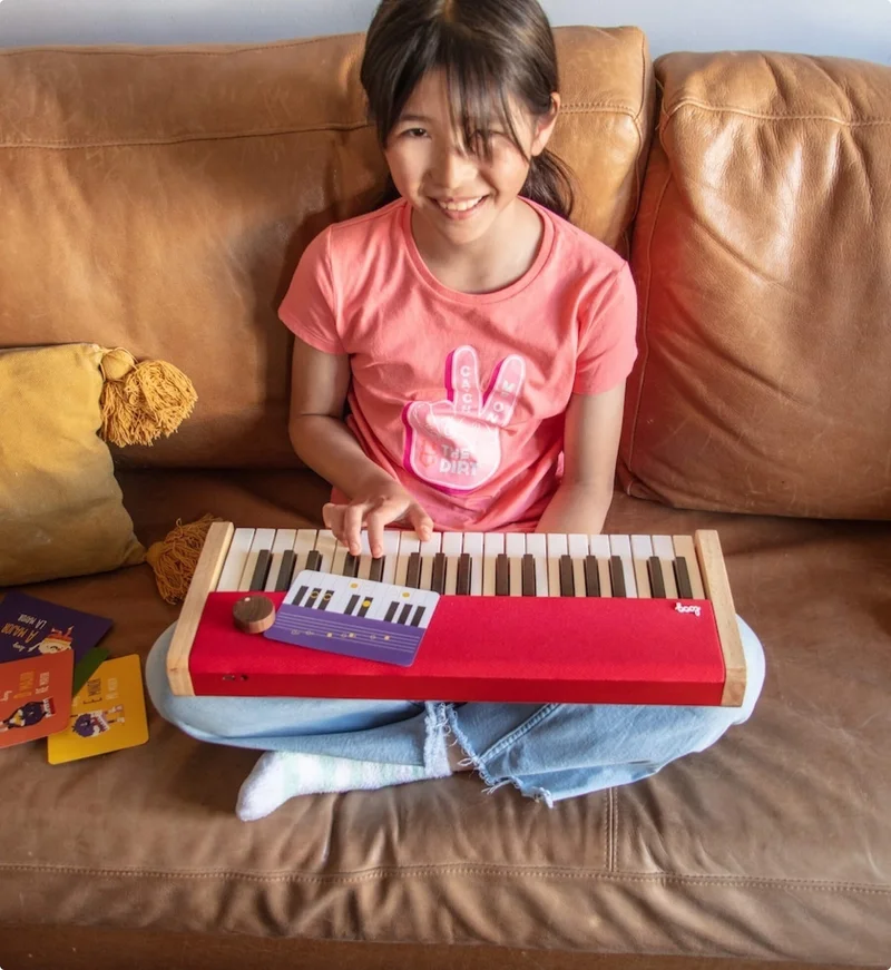 girl playing loog piano with card