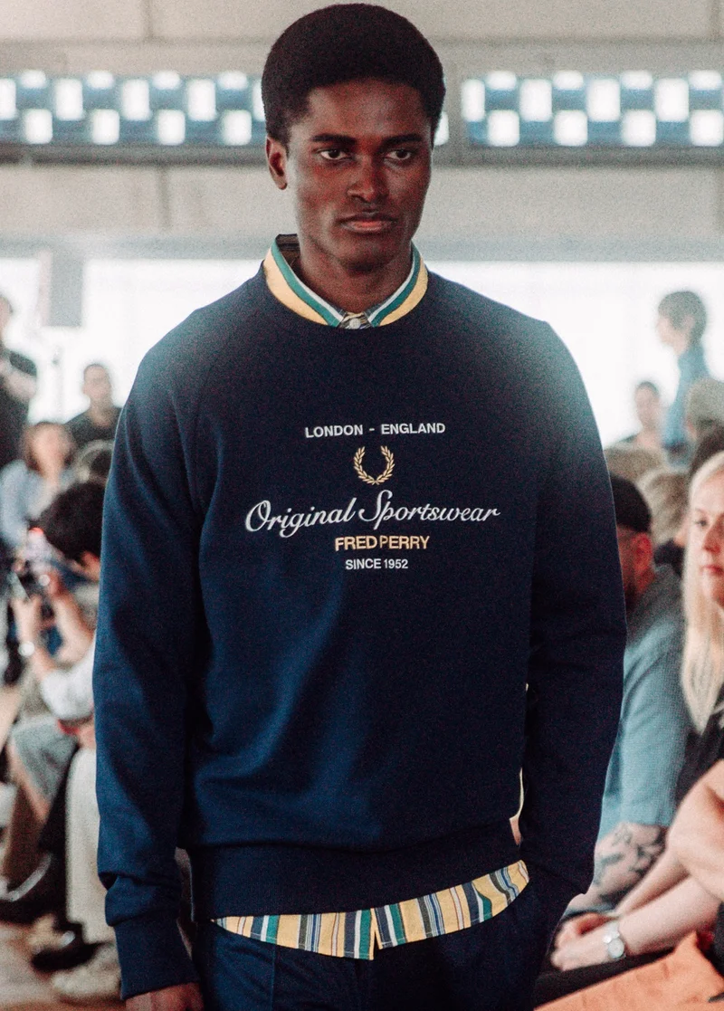 Black male model with short hair walks the runway in our 'Original Sportswear' embroidered logo sweatshirt in navy