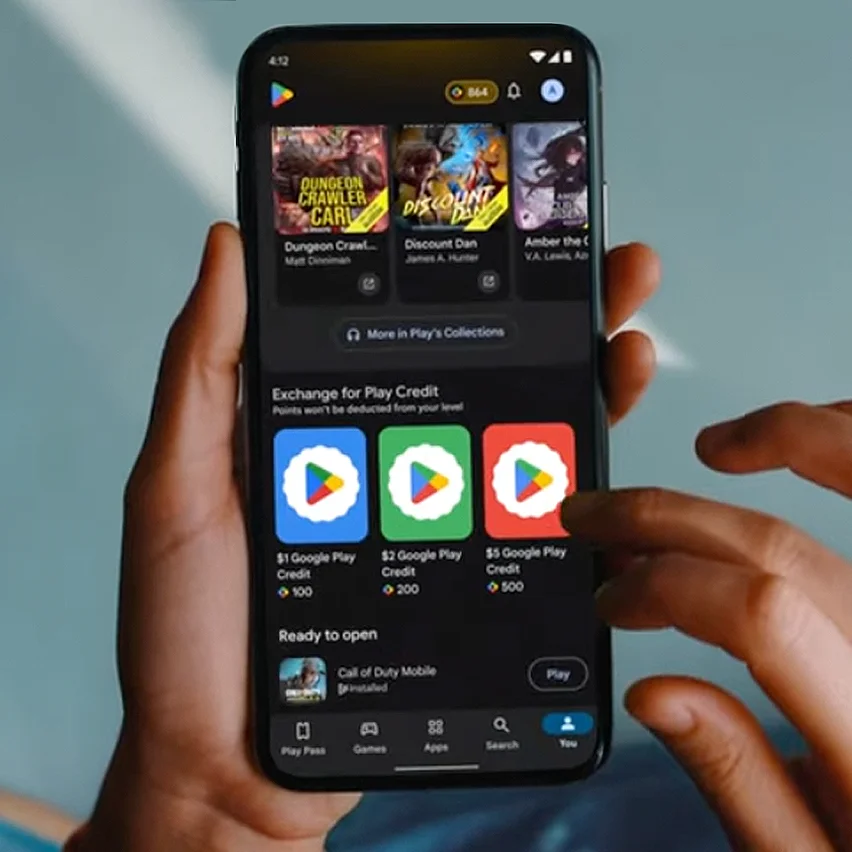 A person holds a smartphone displaying the Google Play Store, featuring a section to exchange points for Play Credit.