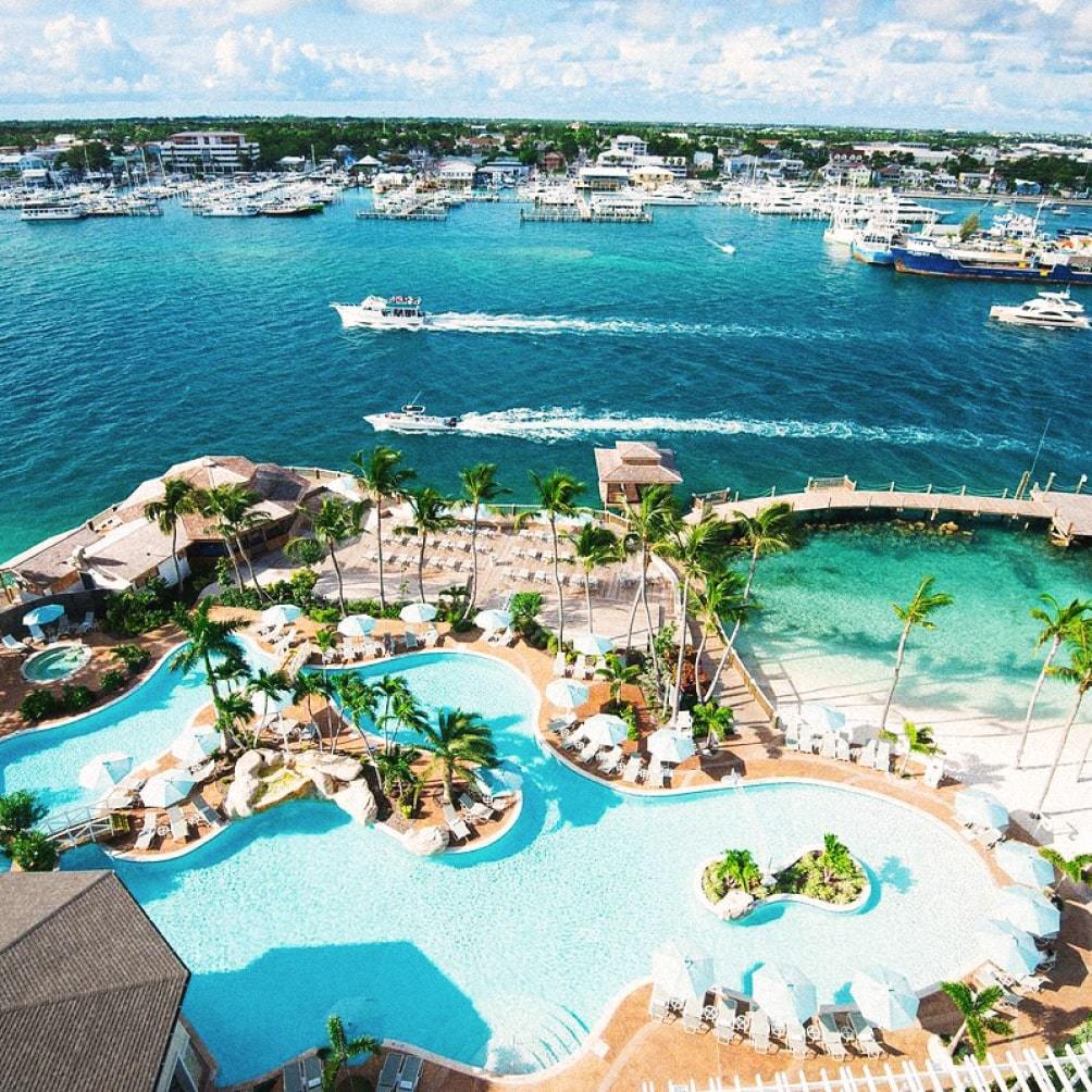 Image Description: An aerial view of yachts cruising past Warwick Paradise Island’s outdoor pool in the Bahamas