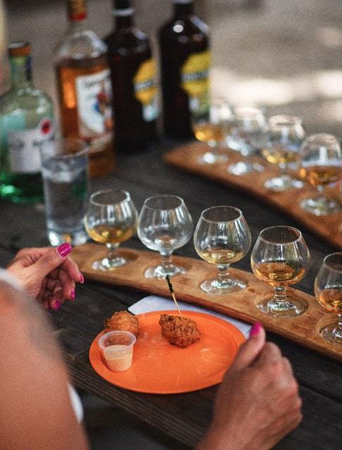 Image Description: A table with a plate of Bahamian conch fritters and a tasting flight of rum
