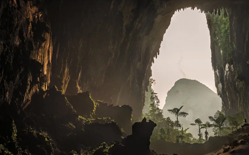 Light carefully covers the inside of a cave at dusk, while off in the distance