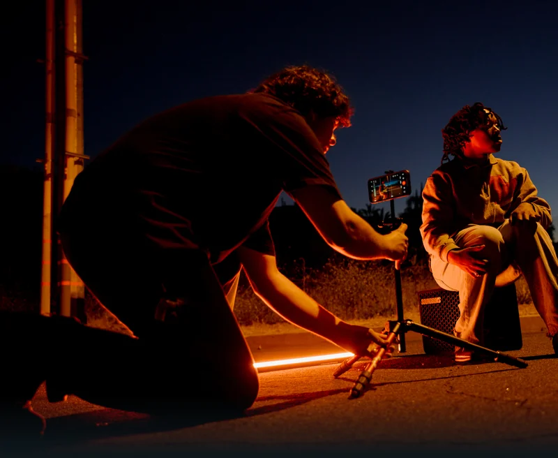 Image of someone filming a music video on their phone outside in the dark with red lighting.