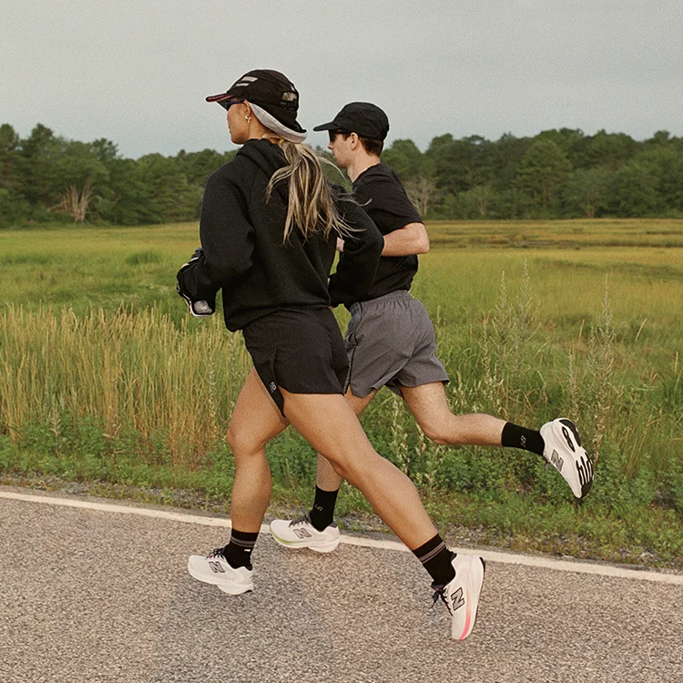 Two people running alongside a green field.