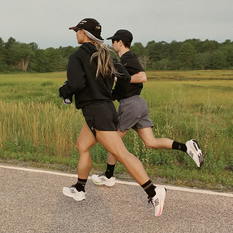 Two people running alongside a green field.