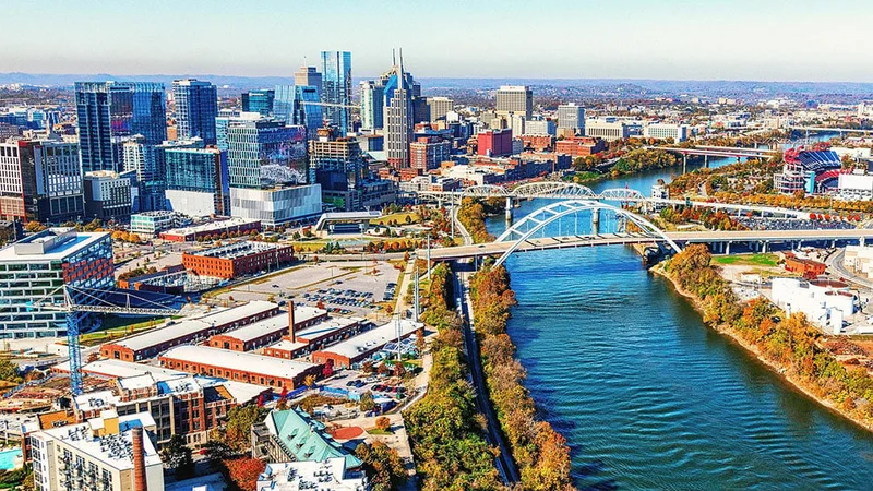 Image description: Aerial view of fall foliage and Nashville skyline