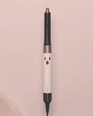 The Dyson Airwrap multi-styler in Ceramic pink and rose gold being revealed by silk