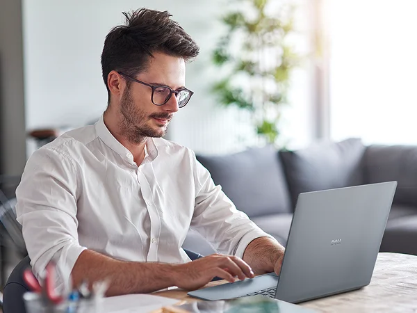 A focused businessperson working on a Dell laptop at home.