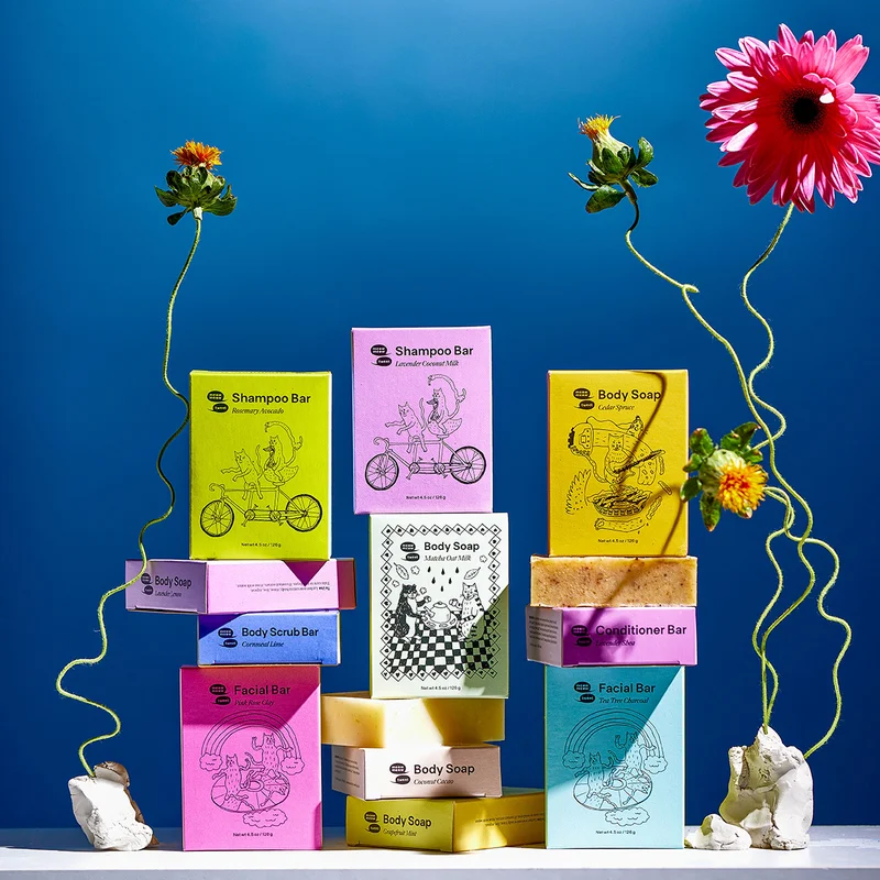 A collection of rainbow boxes of soap stacked and arranged with colorful flowers