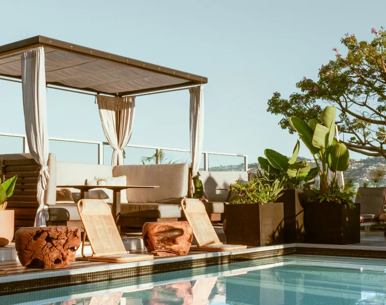 A rooftop pool deck with modern cabanas during golden hour