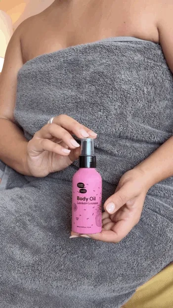 A person's torso and they apply the pink bottle of body oil