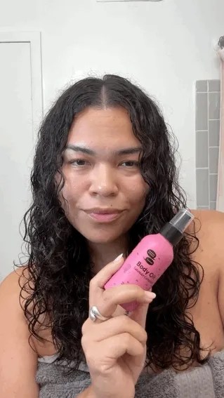A person with long brown curly hair twists their hair to show how to make it curl