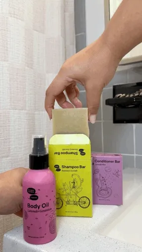 A person with long brown hair washes their hair in the shower