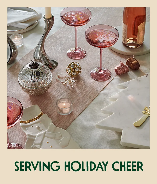 A table set with holiday-themed serving platters, festive decorations and pink glasses.