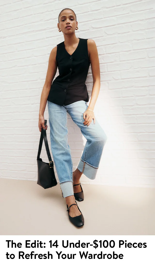 Model wearing a vest with jeans, flats and handbag.