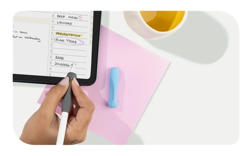 A hand holding an Apple Pencil with Paperlike's Pencil Grip (2nd Generation) in Charcoal over an iPad with Paperlike's Pro Planner on the screen.
