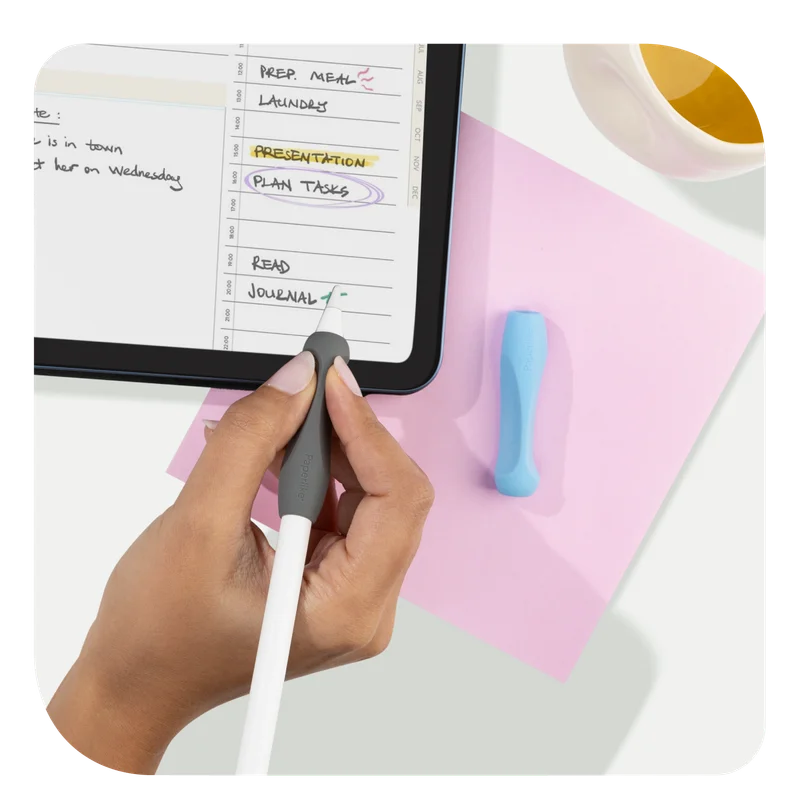 A hand holding an Apple Pencil with Paperlike's Pencil Grip (2nd Generation) in Charcoal over an iPad with Paperlike's Pro Planner on the screen.