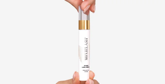 Hand holding Moxielash Xtend Lash and Brow Serum bottle with gold cap