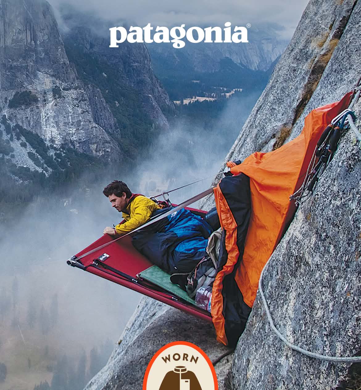 Patagonia. A person looks over the edge of their portaledge, high on a rock wall.