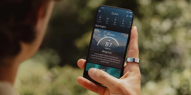 Person wearing Oura Ring holding phone with Oura app open