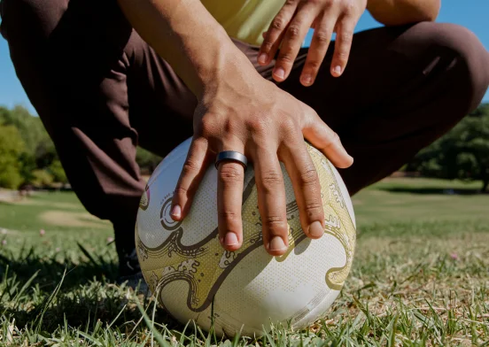 Hand holding soccer ball wearing Oura Ring 4