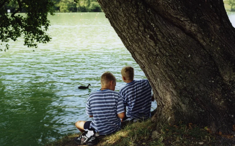 Twins sit near Lake Geneva in Lausanne, Switzerland.