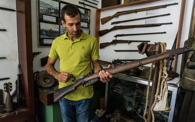 Stelios Tripalitakis holds an original rifle used during the Battle of Crete, part of his extensive collection dedicated to preserving the island’s wartime history and resistance.