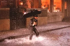 A man with an umbrella splashing puddles.