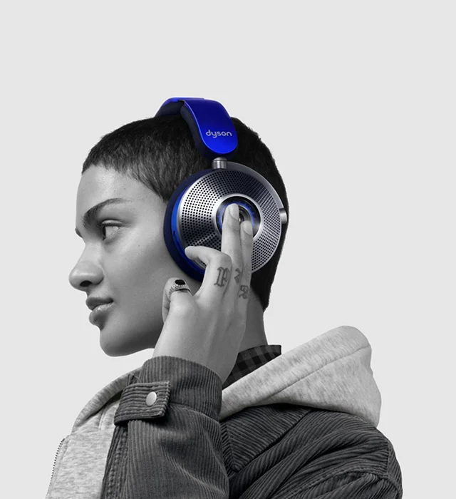 Woman wearing the Dyson Zone noise-cancelling headphones as she touches the back of the ear cup