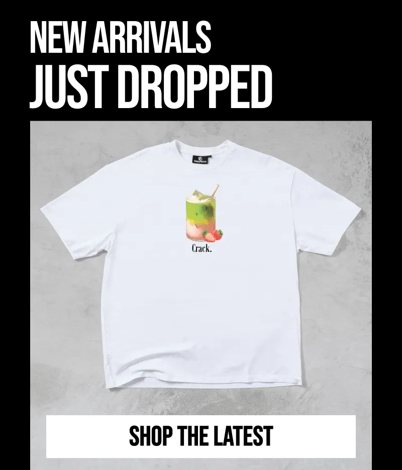 A white t-shirt with a graphic of a layered drink with strawberries and the text 'Crack.' is displayed against a gray concrete background, with 'NEW A...