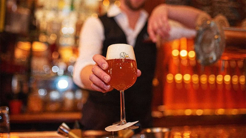 Image description: Bartender serving beer at bar in Amsterdam.