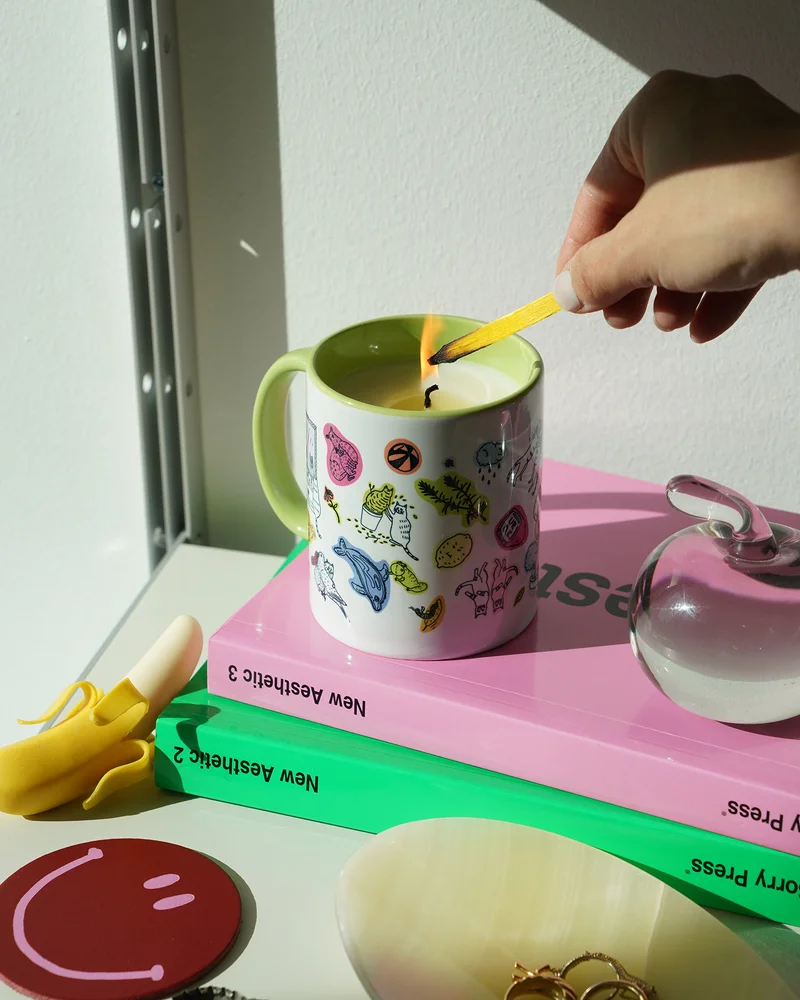 A hand lights the mug-poured anything candle