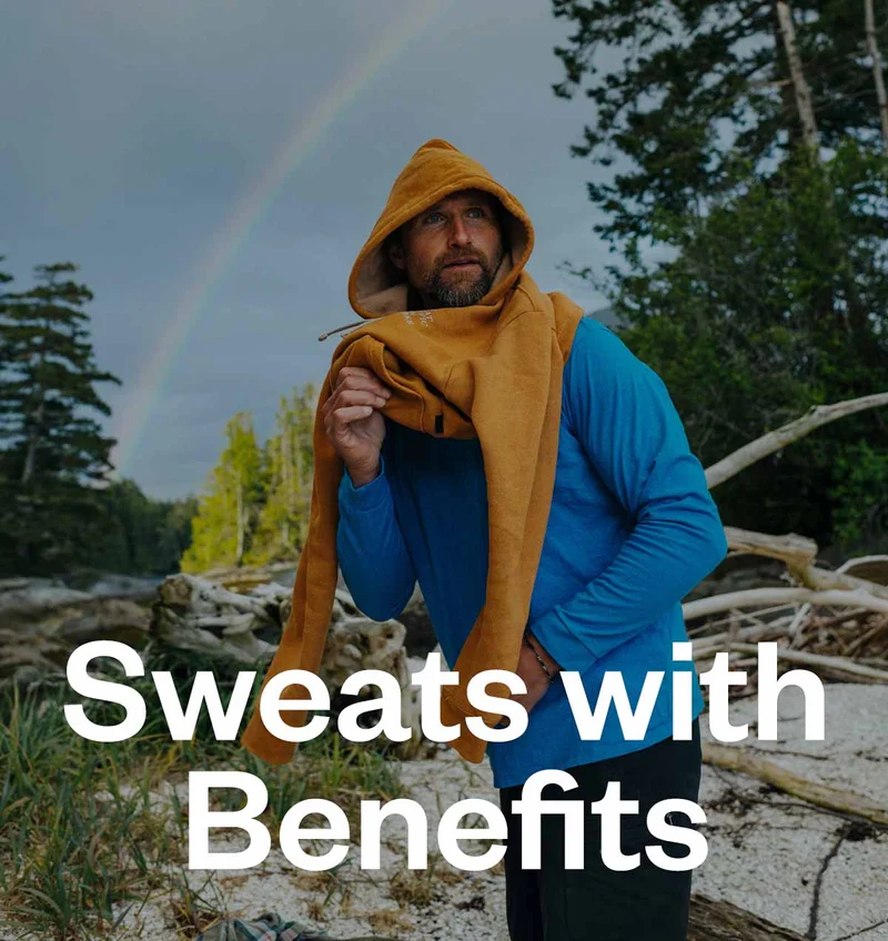 Sweats with benefits. A person puts on an orange sweatshirt with a rainbow in the sky behind them.