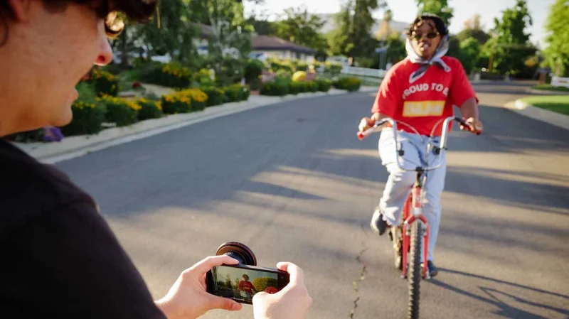 Image of someone filming a bike rider using their phone.