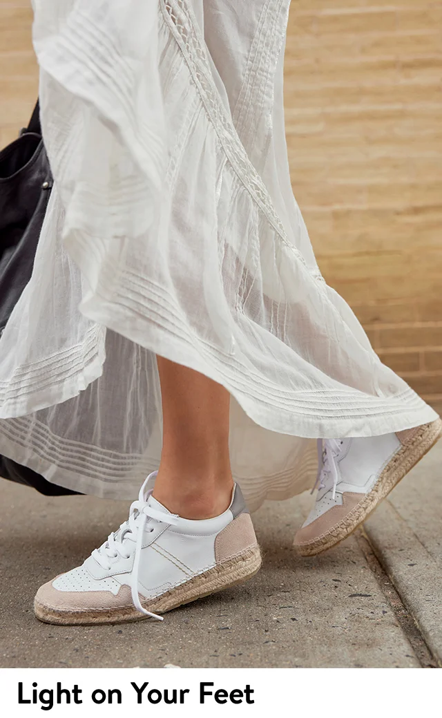 A woman wearing sneakers with a long white skirt.